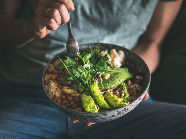 a person holding a bowl of food with a spoon.