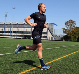 a woman running on a field with a building in the background.