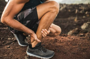 a man tying his shoelaces on a dirt trail.