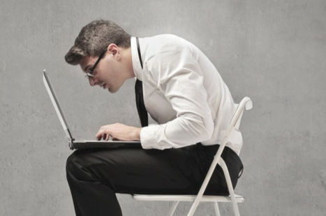 a man sitting on a chair using a laptop computer.