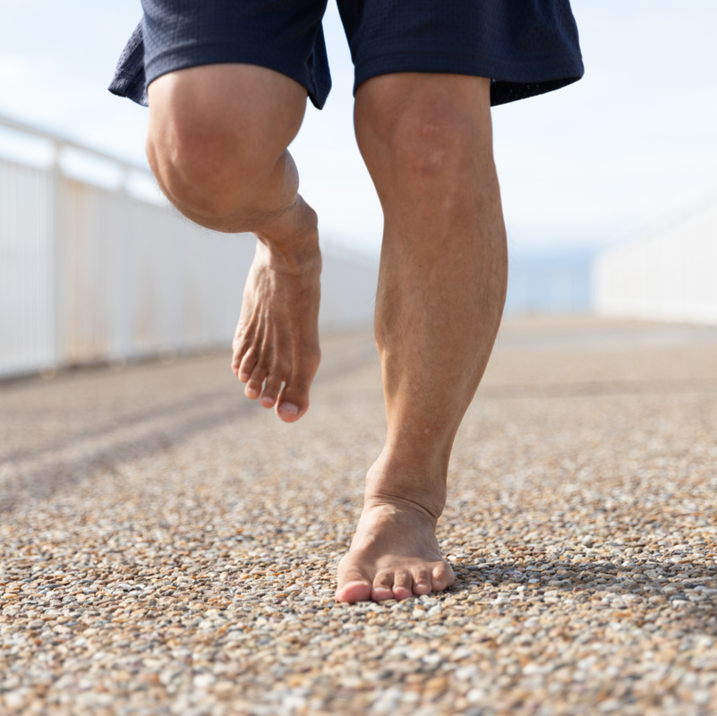 a close up of a person's bare feet walking on gravel.