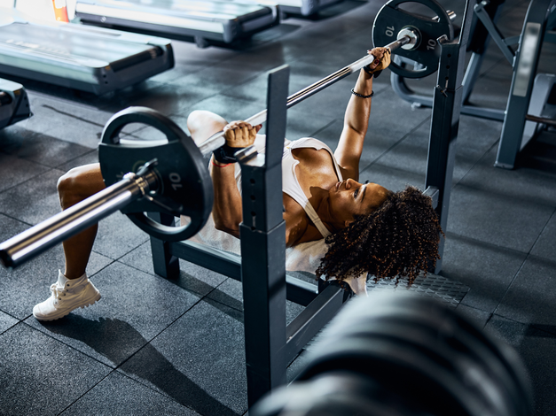 a woman doing a bench press with a barbell.