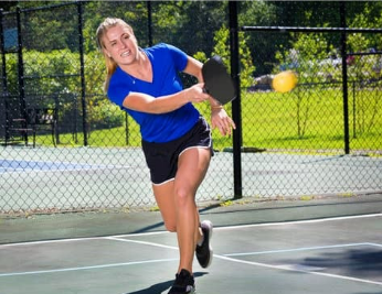 a woman hitting a tennis ball with a racquet.