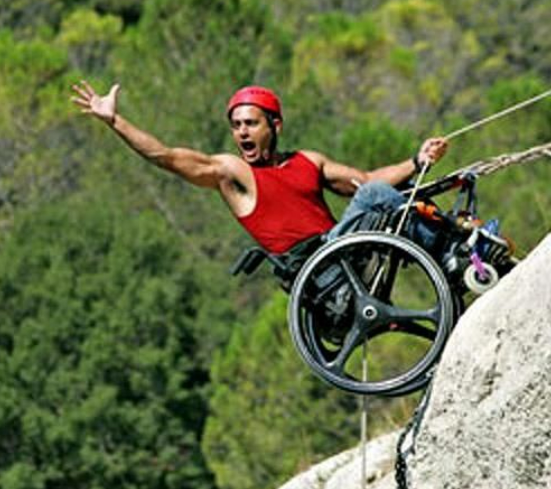 a man in a wheel chair on top of a cliff.