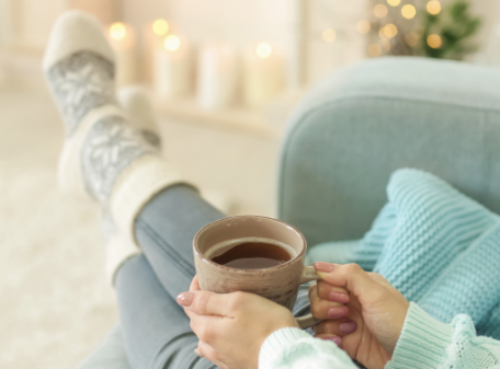 a woman sitting on a couch holding a cup of coffee.