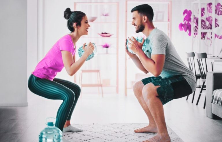 A man and woman doing squats in a living room.