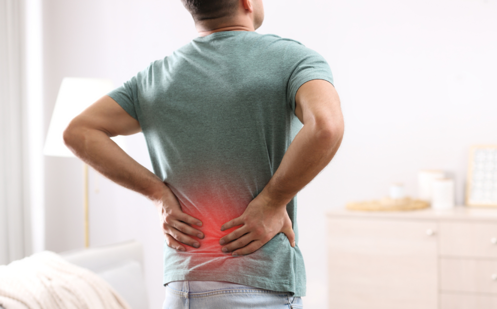 A man with a back pain standing in his living room.