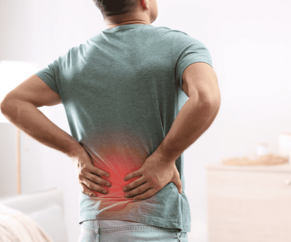 A man with a back pain standing in his living room.