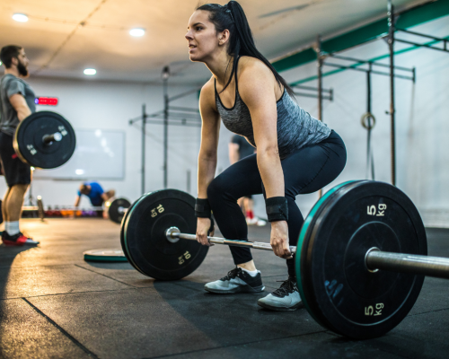 A woman lifting a barbell in a crossfit gym.